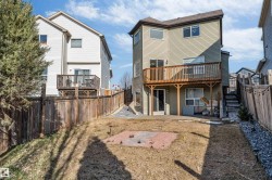 Expansive backyard featuring a multi-level wooden deck, ground-level patio access, and a paved brick area - 