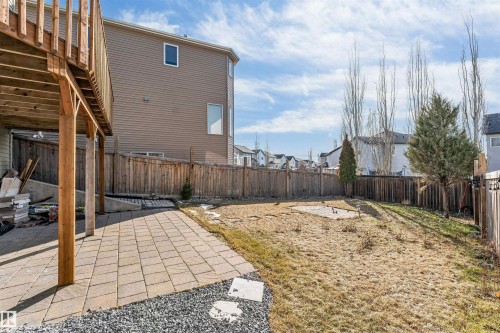 Expansive backyard featuring a wood deck, paver patio, wood fencing, and mature trees - 5928 12 Avenue, Edmonton, AB 
