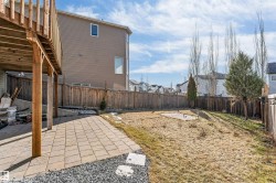 Expansive backyard featuring a wood deck, paver patio, wood fencing, and mature trees - 