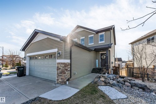 Contemporary two-story residence featuring light green siding, a two-car garage, and stone accent detailing - 5928 12 Avenue, Edmonton, AB 