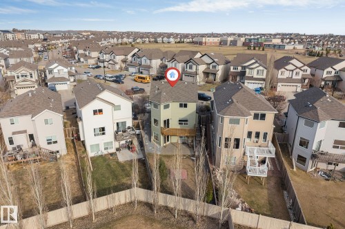 Two-story residence featuring a light green exterior siding, a multi-level deck, and a fenced backyard - 5928 12 Avenue, Edmonton, AB 