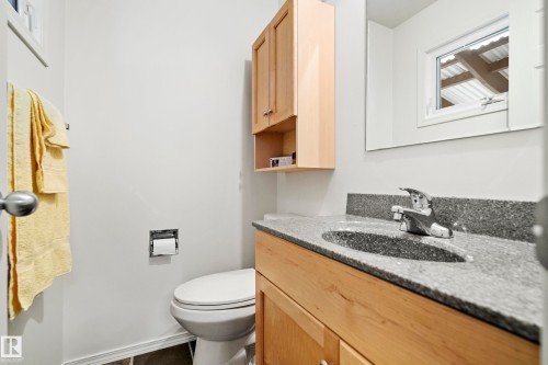 Bathroom featuring a light wood-finish vanity with a speckled countertop and integrated sink - 3208 70 Street, Edmonton, AB 
