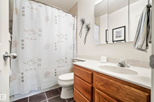Bathroom featuring a wood-finish vanity with a single basin sink and light-colored countertop - 3208 70 Street, Edmonton, AB 
