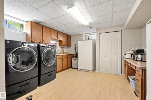Utility room featuring wood-finish cabinetry, light-toned countertops, and vinyl plank flooring - 3208 70 Street, Edmonton, AB 