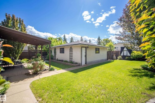 Spacious backyard featuring a detached garage, a covered patio area, and a large lawn - 3208 70 Street, Edmonton, AB 