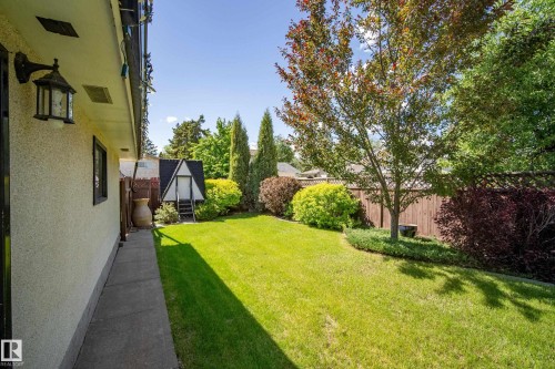 Expansive backyard featuring a manicured lawn, mature trees, and established shrubbery - 3208 70 Street, Edmonton, AB 
