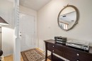 White multi-panel entry door with brass hardware, light wood-finish flooring, and a decorative wall partition - 3208 70 Street, Edmonton, AB 