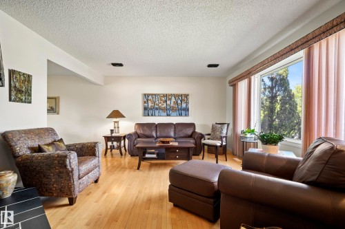 Expansive window with privacy drapes, light wood-finish flooring, white painted walls, and a textured ceiling - 3208 70 Street, Edmonton, AB 