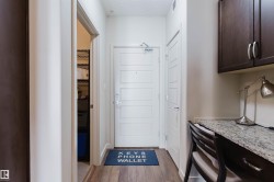 Entryway featuring wood-finish flooring, a contemporary paneled door, and an integrated desk area - 