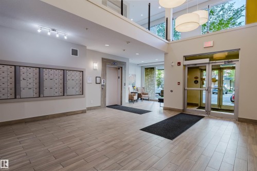 Two-story lobby with light wood-finish flooring, a wall of secure mailboxes, and an elevator - 217 508 Griesbach Parade, Edmonton, AB 