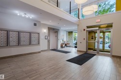 Two-story lobby with light wood-finish flooring, a wall of secure mailboxes, and an elevator - 