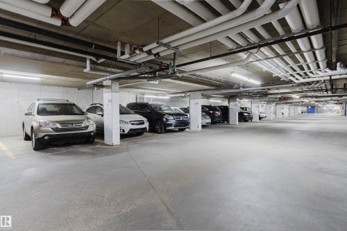 Covered parking garage featuring concrete flooring, concrete walls, and overhead lighting - 217 508 Griesbach Parade, Edmonton, AB 