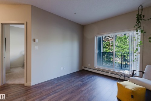 Warm wood-finish flooring complements light-colored walls in this inviting living space - 217 508 Griesbach Parade, Edmonton, AB 