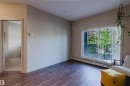 Warm wood-finish flooring complements light-colored walls in this inviting living space - 217 508 Griesbach Parade, Edmonton, AB 