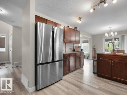 Stainless steel refrigerator framed by light wood-finish flooring - 3756 8 Street, Edmonton, AB 