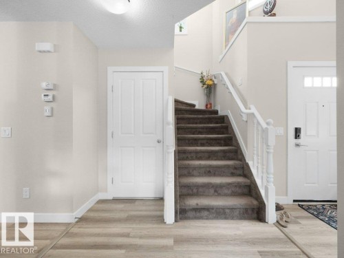 Central staircase with carpeted treads and white wood balusters, complemented by wood-finish flooring - 3756 8 Street, Edmonton, AB 