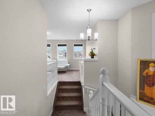 Carpeted staircase descending from an upper level with white painted balusters and railings - 3756 8 Street, Edmonton, AB 