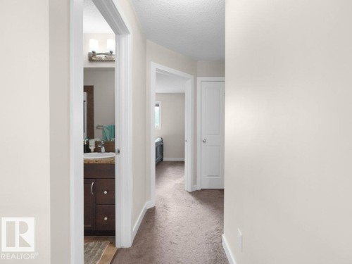 Hallway featuring neutral-toned walls, carpet flooring, white trim, and doors - 3756 8 Street, Edmonton, AB 