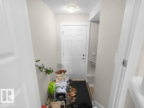 Entryway featuring a paneled door, flush-mount ceiling light, light beige wall paint, white trim, and wood-finish flooring - 3756 8 Street, Edmonton, AB 