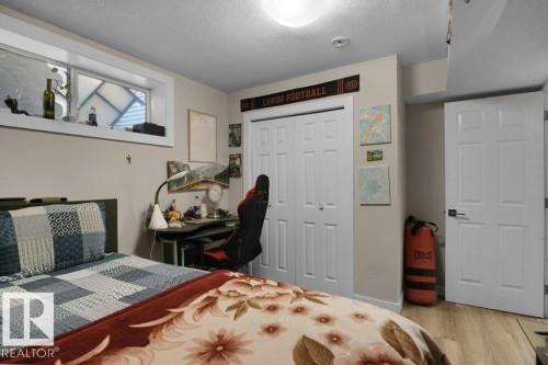 Room featuring wood-finish flooring, a six-panel bi-fold closet, a six-panel door with black hardware, a high-set window, and a flush mount ceiling light - 3756 8 Street, Edmonton, AB 