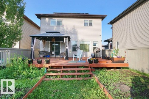 Rear exterior with a wood-finish deck and stairs leading to a ground-level area - 3756 8 Street, Edmonton, AB 