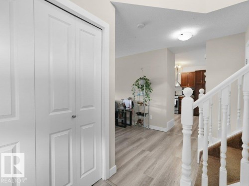 Entryway featuring light wood-finish flooring, white bi-fold closet doors, and painted white balusters - 3756 8 Street, Edmonton, AB 