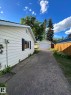 Property exterior featuring light-colored horizontal siding, black window shutters, and a concrete driveway leading to a detached garage - 13112 63 Avenue, Edmonton, AB 