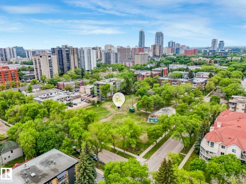 Urban landscape featuring a mix of residential and commercial buildings, interspersed with mature green trees - 403 10165 113 Street, Edmonton, AB 