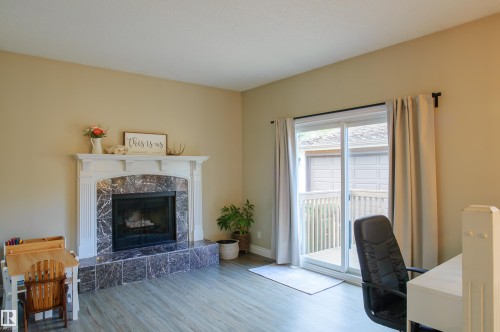 Fireplace featuring a white mantel, dark stone surround, and hearth - 58 Lodgepole Crescent, St. Albert, AB 