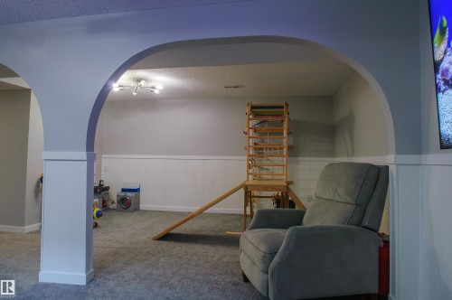 Arched entryway leading to a carpeted room featuring wainscoting and recessed lighting - 58 Lodgepole Crescent, St. Albert, AB 