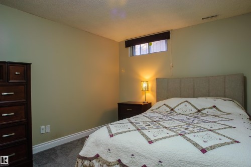 Basement bedroom, carpeted room featuring light-toned walls, a small window with a dark roller shade, and white baseboards - 58 Lodgepole Crescent, St. Albert, AB 