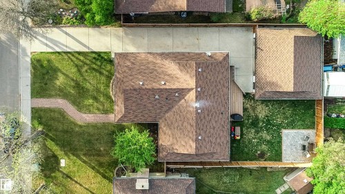 Aerial property overview featuring a brown shingle roof, a generously sized driveway, and a fenced backyard with a patio area - 58 Lodgepole Crescent, St. Albert, AB 
