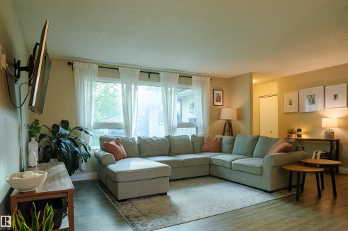 Open living area featuring wood-finish flooring, a broad window, and neutral wall tones - 58 Lodgepole Crescent, St. Albert, AB 