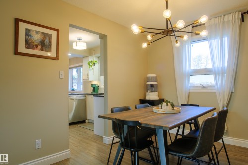Dining area featuring a contemporary sputnik chandelier, wood-finish flooring, and an architectural opening to the kitchen - 58 Lodgepole Crescent, St. Albert, AB 
