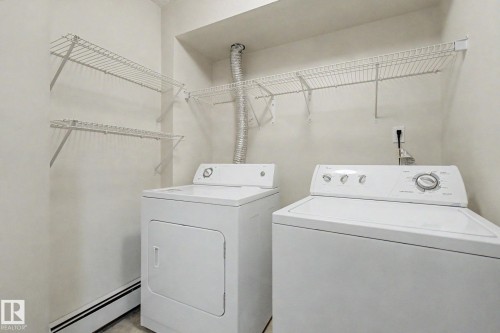 Dedicated laundry area featuring a washer and dryer, white wire shelving, baseboard heating, and light-colored walls - 11150 83 Avenue, Edmonton, AB 