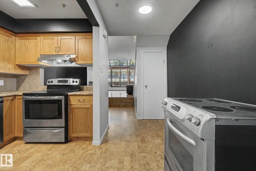 Kitchen featuring stainless steel appliances, light wood cabinetry, tiled backsplash, and stone-finish countertops - 11150 83 Avenue, Edmonton, AB 