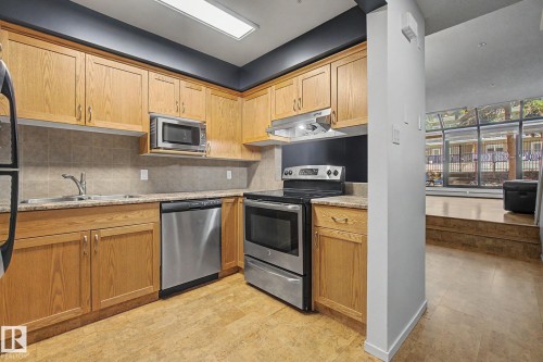 Kitchen featuring wood cabinetry, stainless steel appliances, and a tile backsplash - 11150 83 Avenue, Edmonton, AB 