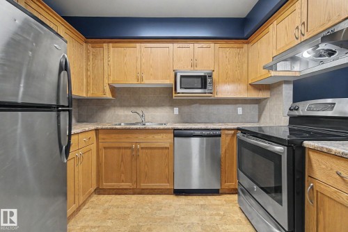Kitchen featuring ample wood cabinetry, stainless steel appliances, a tile backsplash, and durable laminate countertops - 11150 83 Avenue, Edmonton, AB 