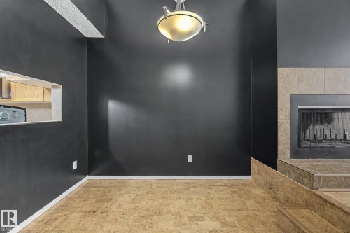 Recessed fireplace with a tiled surround, complemented by an overhead light fixture - 11150 83 Avenue, Edmonton, AB 