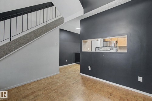 Staircase with black metal railing and grey carpet runner, complemented by wood-finish flooring - 11150 83 Avenue, Edmonton, AB 