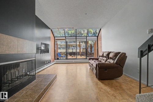 Living area featuring wood-finish flooring and a fireplace with a tiled hearth and surround - 11150 83 Avenue, Edmonton, AB 