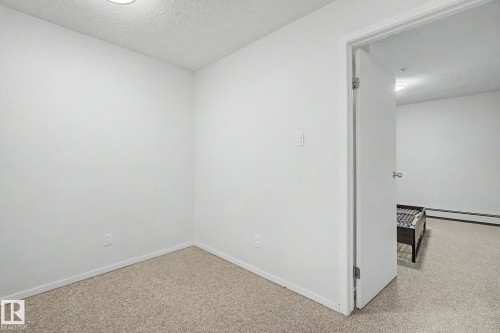 Room featuring light-colored wall-to-wall carpeting, white baseboards, and a flush-mount ceiling light - 11150 83 Avenue, Edmonton, AB 