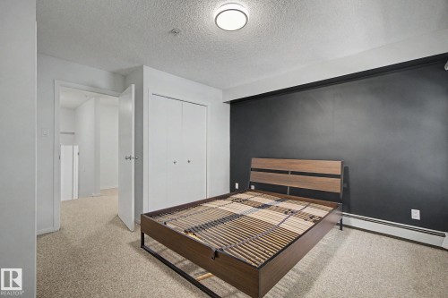 Bedroom featuring a dark accent wall, neutral carpeting, and a flush-mount ceiling light - 11150 83 Avenue, Edmonton, AB 