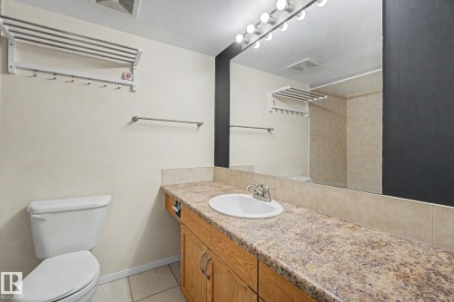 Bathroom vanity featuring a speckled countertop, a drop-in sink with a chrome faucet, and wood-finish cabinetry - 11150 83 Avenue, Edmonton, AB 
