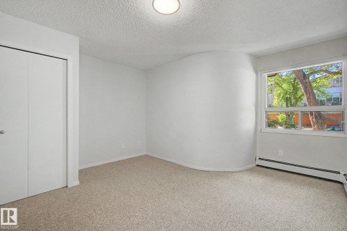 Bright room featuring a large window, neutral carpeting, and a built-in closet with bifold doors - 11150 83 Avenue, Edmonton, AB 
