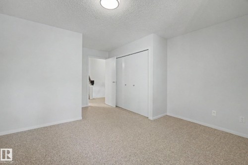 Carpeted room featuring neutral wall tones, a built-in closet with bi-fold doors, and a ceiling-mounted light fixture - 11150 83 Avenue, Edmonton, AB 