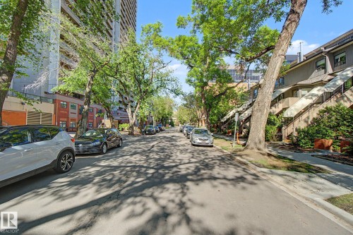 Residential street with mature tree canopy and townhouse-style properties featuring individual exterior staircases with awnings - 11150 83 Avenue, Edmonton, AB 