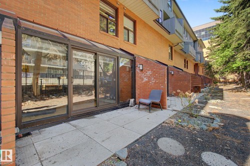 Expansive brick exterior with a lower-level patio featuring large sliding glass doors - 11150 83 Avenue, Edmonton, AB 