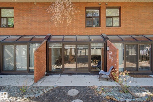 Brick exterior featuring a glass-enclosed patio with multiple sliding glass doors and transom windows - 11150 83 Avenue, Edmonton, AB 