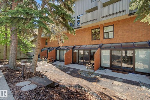 Ground-level patio entry featuring multiple sliding glass doors and an extended glass enclosure - 11150 83 Avenue, Edmonton, AB 